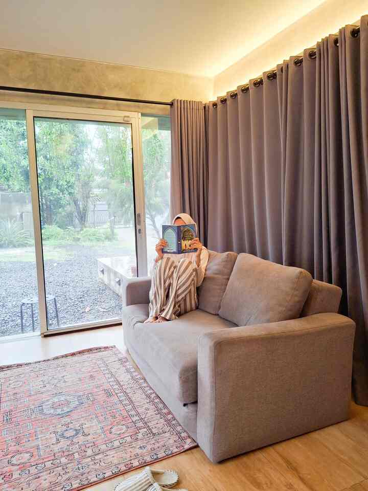 Cozy living room with gray curtains and beige sofa, illuminated by natural light through glass sliding door