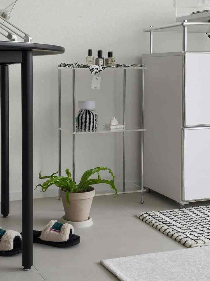 Natural tone living room corner featuring transparent acrylic shelves and silver frame with a modern, clean atmosphere