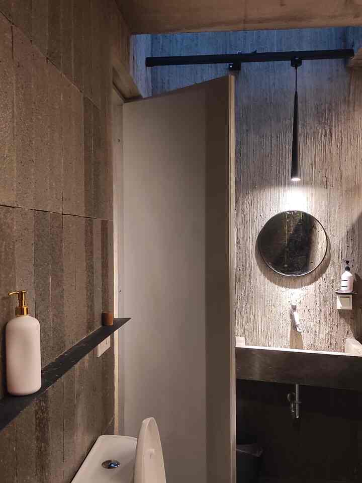 Kamar mandi di kantor kami berkonsep Tropis Natural yang menyatu dengan alam. Kamar mandi bisa jadi tempat yang nyaman dengan perpaduan warna material yang apa adanya. Perpaduan material alami seperti batu pecah, batu andesit, tekstur dari semen asli menjadi nuansa baru di kamar mandi yang mayoritas berwarna abu. Di area basah, diperhangat dengan tambahan tanaman sirih gading yang menjuntai dan tumbuh alami. Nuansa hangat terasa saat malam hari saat semua lampu di kamar mandi menyala. 
Jadi terasa unik dan beda kan? 

#lampukamarmandi #dindingkamarmandi #keran #kranair #cerminkamarmandi #botolsabun #botolshampo #stopkontak #stopkontaktutup 
#RenovasiKamarMandi
#BathroomMakeOver
#InspirasiKamarMandi
