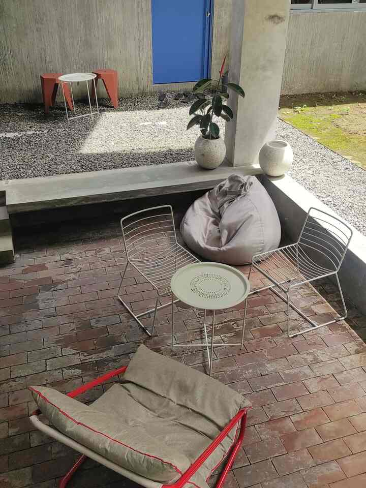Gray and brown toned outdoor balcony featuring metal outdoor chairs, a table, a beige bean bag, and a plant with a modern vibe