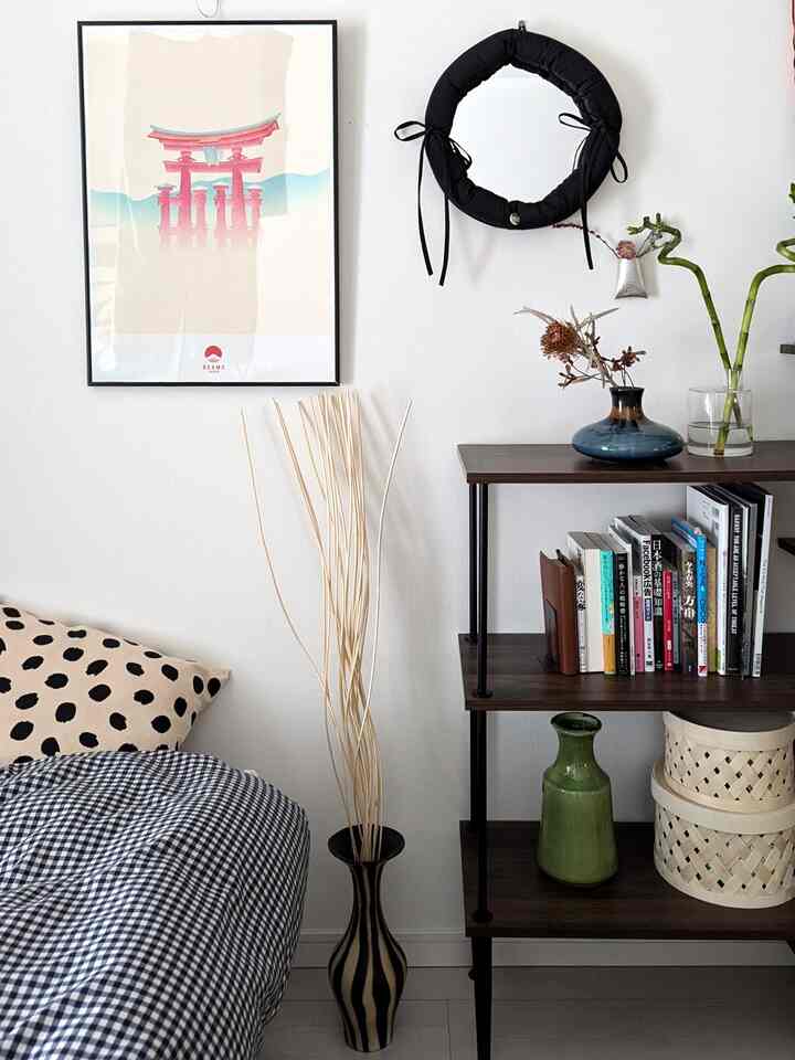 Bright white wall bedroom featuring black accents and natural wood tone shelf, with cushions and vases adding cozy decor