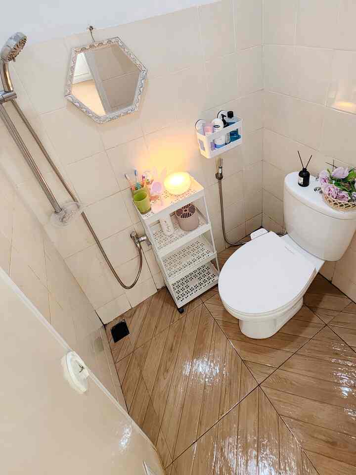 White and brown toned bathroom featuring a shower head and storage rack, creating a clean and cozy atmosphere