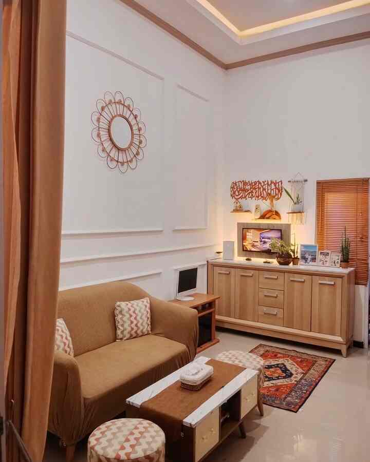 Natural warm tones and wood accents define this compact living room featuring a brown sofa, round mirror, and wooden blinds in a simple, cozy setting