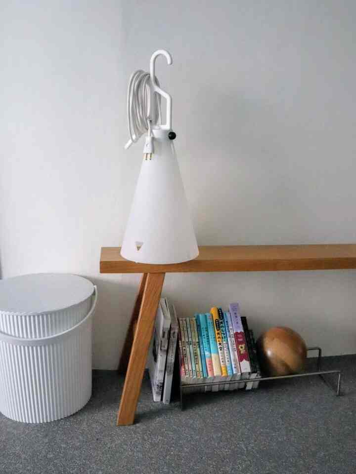 白と木目調が調和するリビング、ベンチとフロアランプ、本棚が配置されたミニマルな雰囲気のインテリア