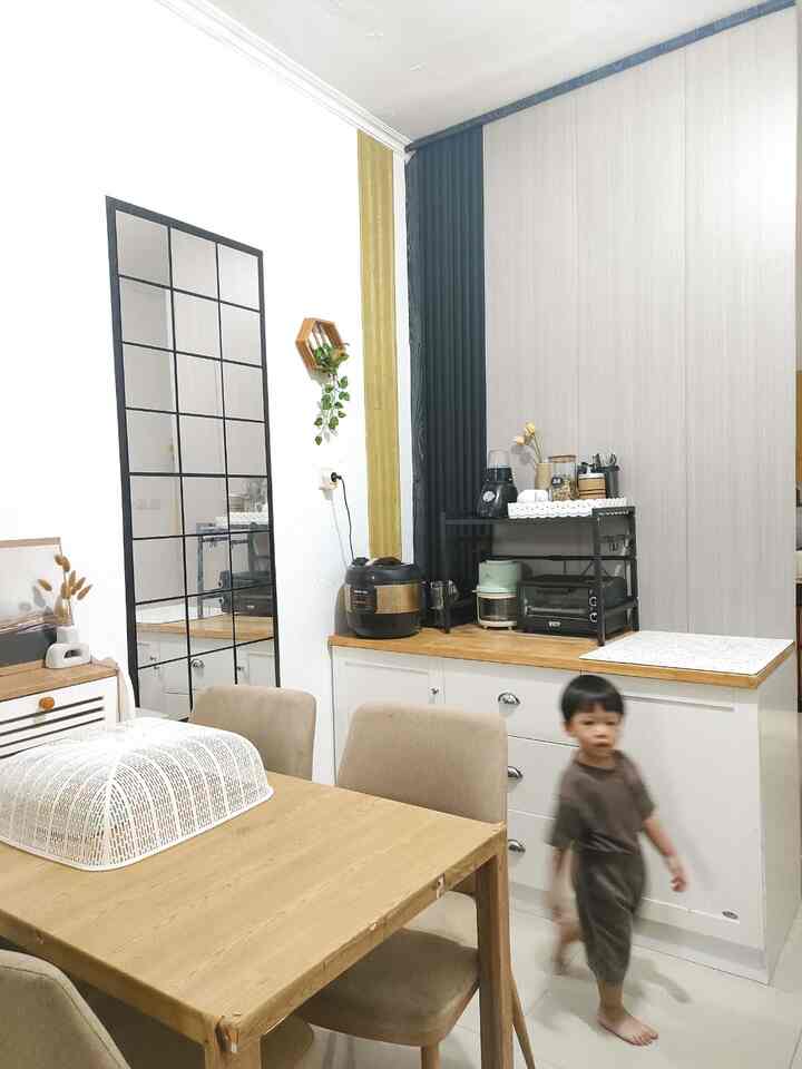 Simple kitchen space with white and wood tones, featuring a large grid-style wall mirror enhancing the sense of openness