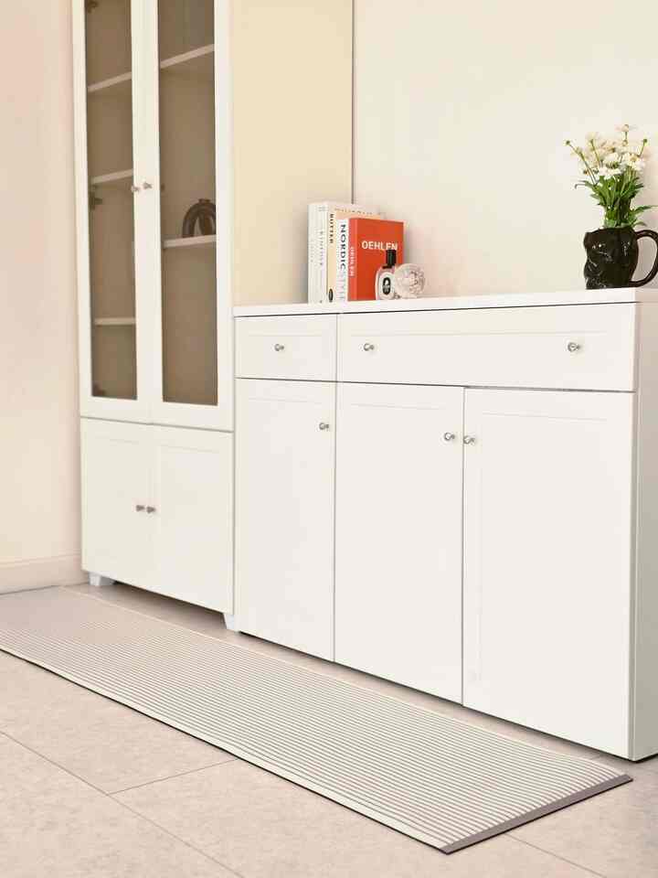 ナチュラルカラーとホワイトのキッチン空間、珪藻土マットと整然とした収納キャビネットが配置されたミニマルで落ち着いたインテリア