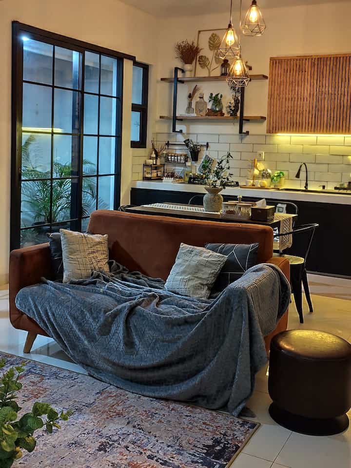 Natural modern living room and kitchen with brown sofa and pendant lighting