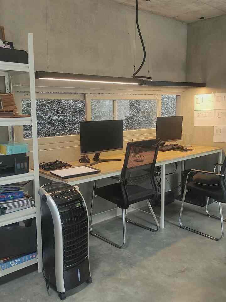 Monotone-toned home office space featuring a long desk with two monitors and office chairs in a clean, organized setting.