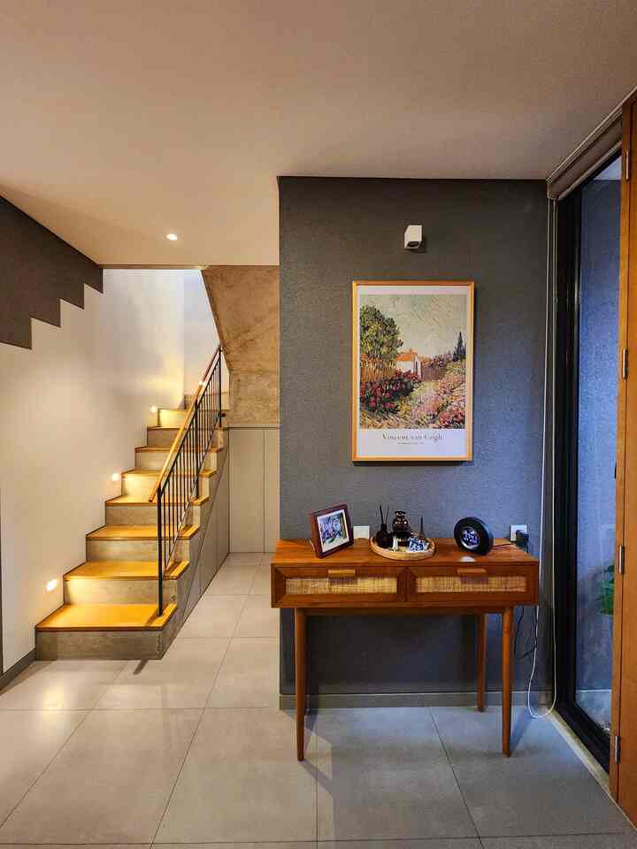 Natural-toned entrance featuring a wood-tone console table and a central Vincent van Gogh framed artwork, showcasing a modern and cozy interior