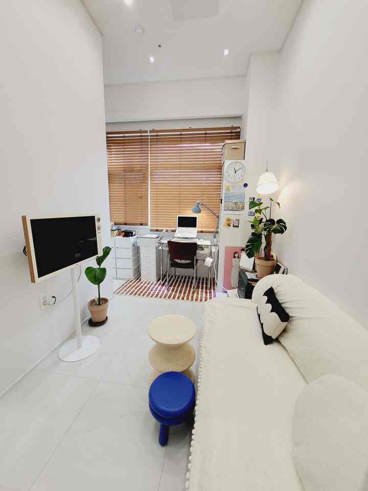 白と木目調の調和が取れたワンルームのホームオフィスとリビングが整然と配置された現代的なインテリア