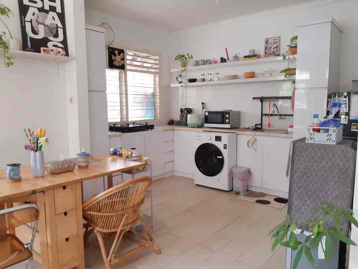 White and wood tone kitchen and dining room featuring dining table, chairs, appliances, and plants creating a cozy atmosphere