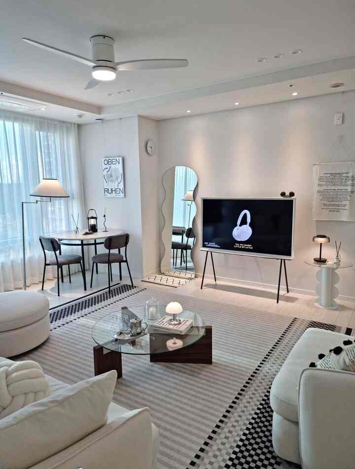 明るくモダンなナチュラルカラーのリビング、シーリングファンと円形コーヒーテーブル、ソファが配置された清潔感のあるインテリア