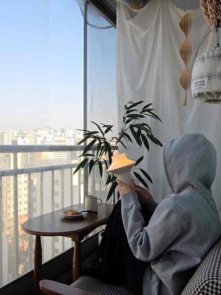 Gray and wood-tone balcony space featuring a side table and plant with a cozy modern home cafe atmosphere