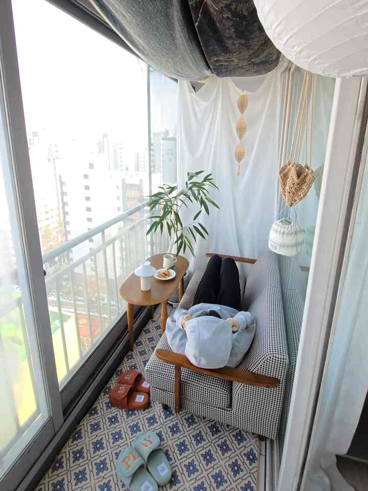 Natural color balcony featuring houndstooth sofa, wooden side table, and green plant in a cozy arrangement