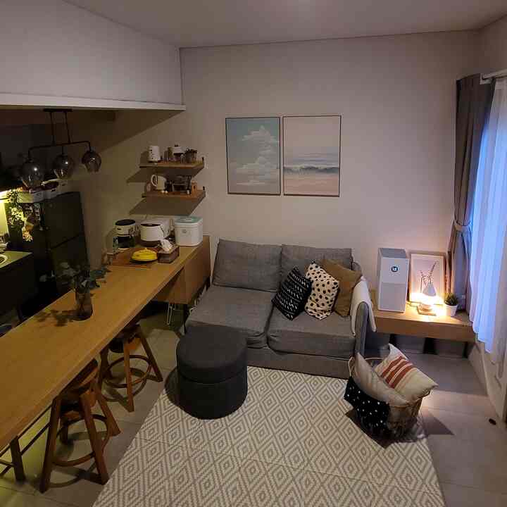 Natural wood tones and gray living room integrated with kitchen in a compact open space including a baby playmat area