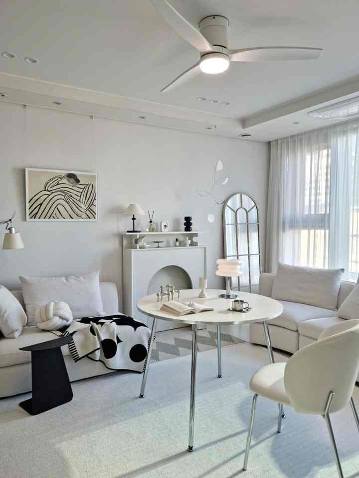 Matte cream-white and silver toned living room featuring a round table and sectional sofa with a modern and bright atmosphere