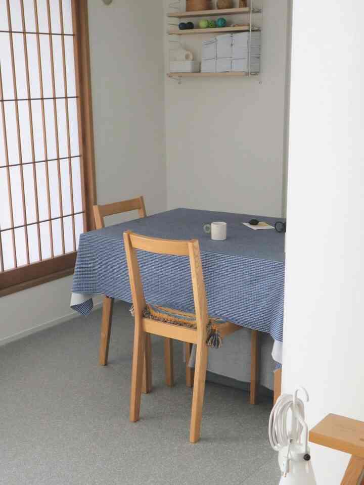 白い壁と木目調の家具が調和するダイニングのコーナー、青いテーブルクロスがかかった食卓と椅子が配置された自然な雰囲気の空間