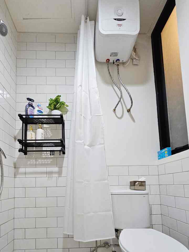 White tiled long narrow bathroom featuring white shower curtain and toilet with a clean minimalist interior