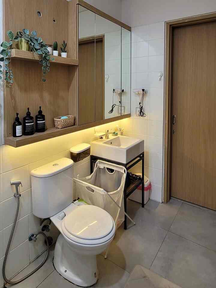 White and natural color toned bathroom featuring washbasin and toilet with clean and organized atmosphere
