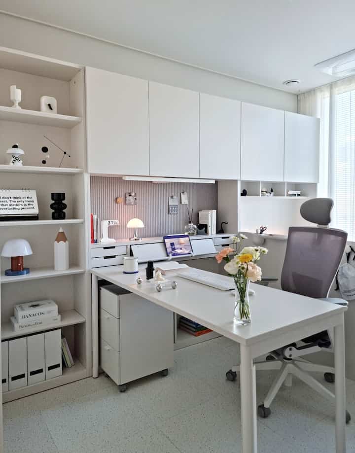 明るく清潔感のあるホワイトトーンのホームオフィス、広いデスクと人間工学に基づいたチェアが配置されたモダンで整理された作業空間