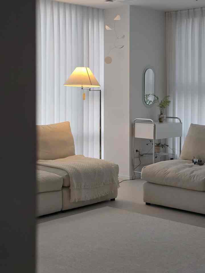 Natural beige and white toned living room featuring two sofas and a floor lamp with a simple and cozy atmosphere