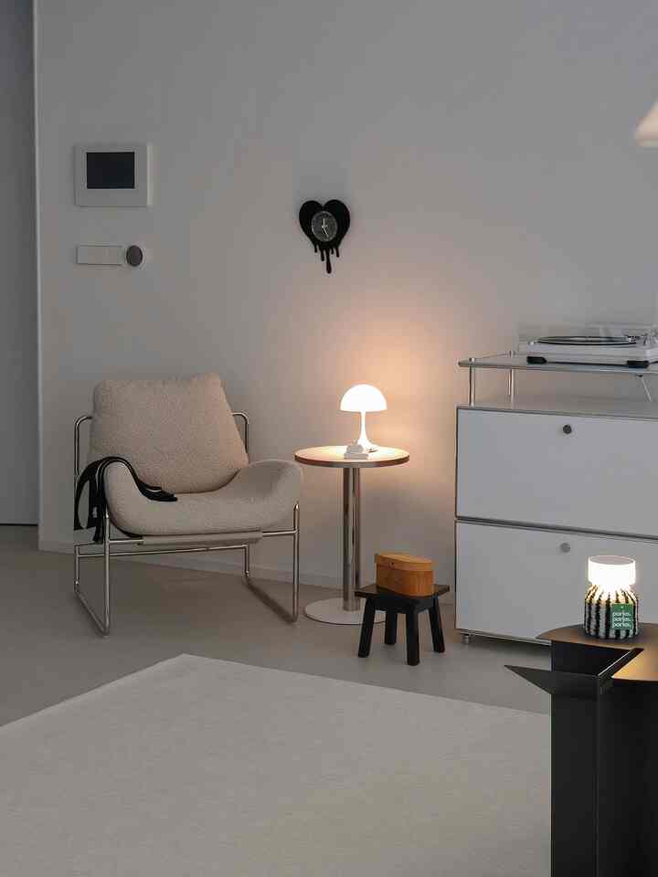 White and beige toned living room featuring a minimalist armchair and side table with a cozy atmosphere