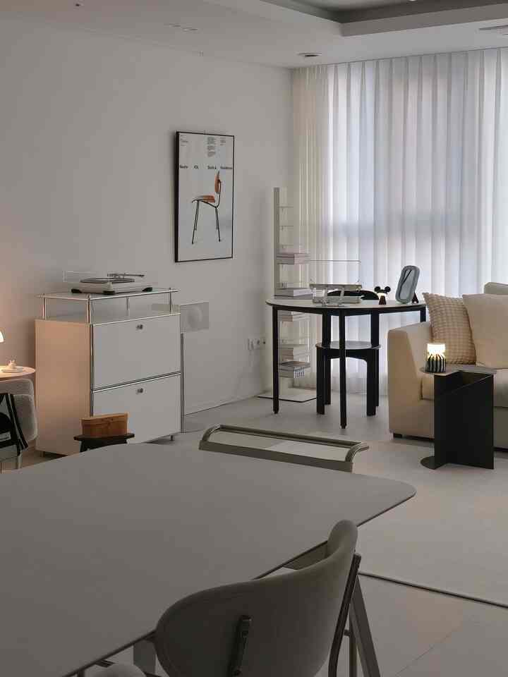 白と黒のトーンのリビング、ミッドセンチュリーモダンの家具とシンプルなダイニングテーブルが配置された印象的なインテリア