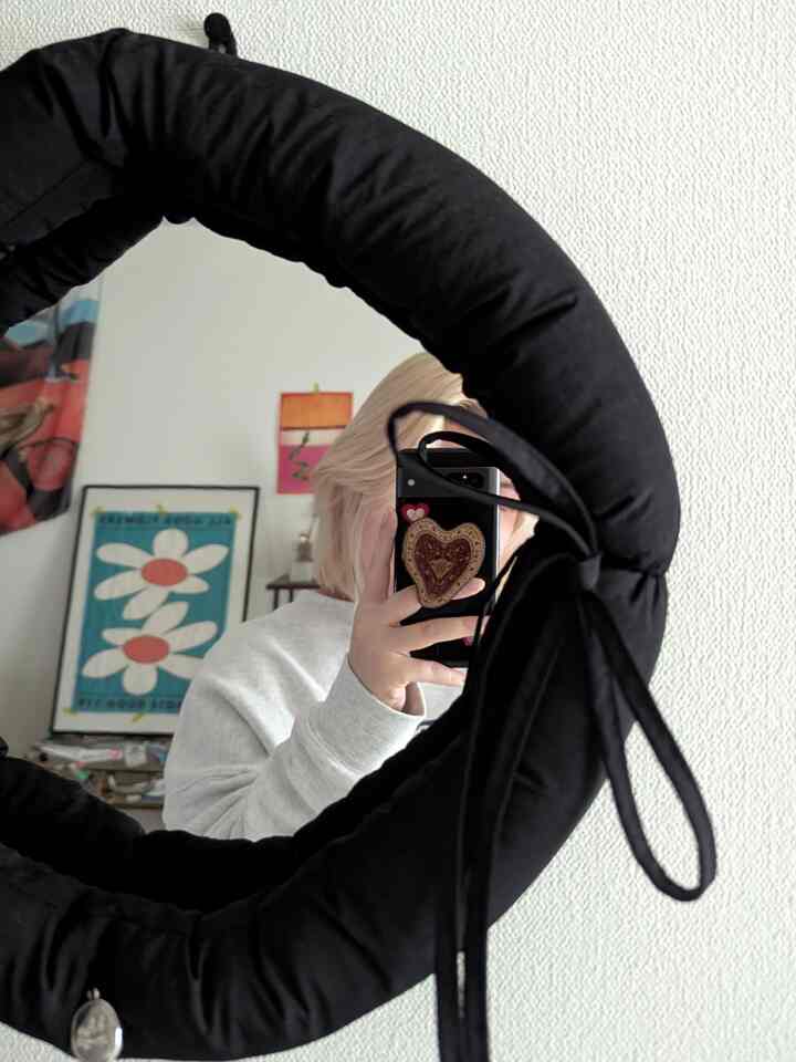 白い壁を背景に黒のパディングミラーが中央に配置された韓国風インテリア