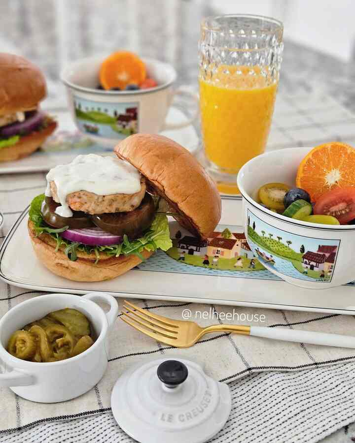 White tablecloth dining setting featuring shrimp burger, fruit bowls, and gold fork creating a sophisticated home cafe atmosphere