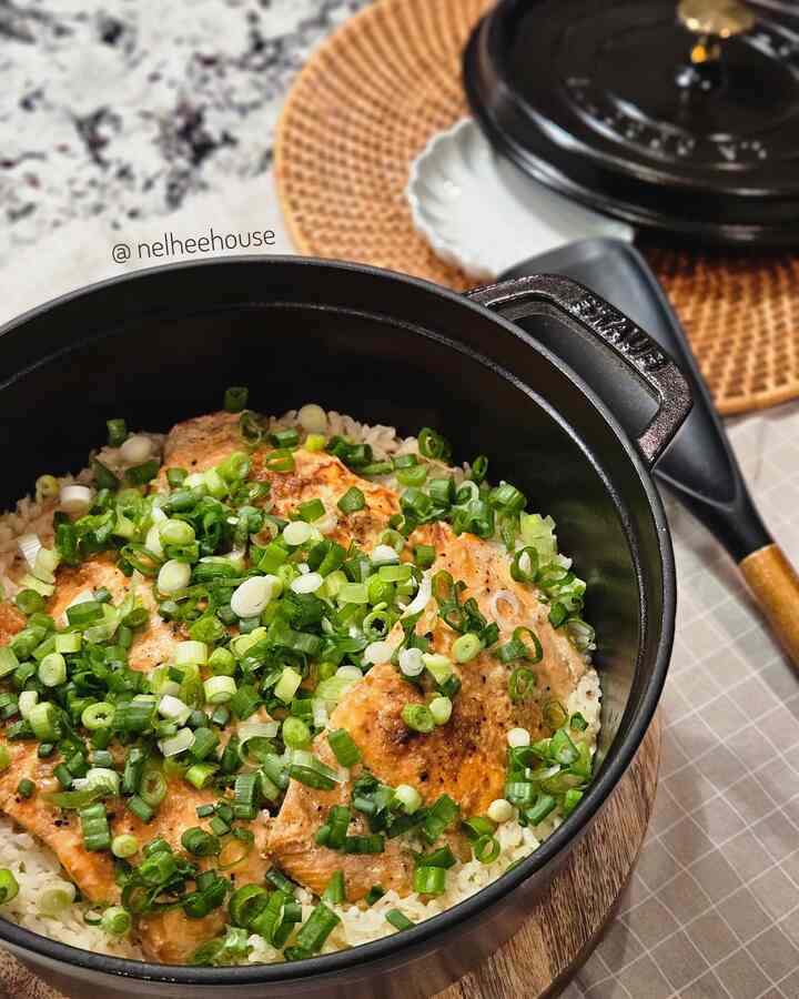 Black Staub pot with delicious salmon and scallions plated rice, kitchen cookware scene