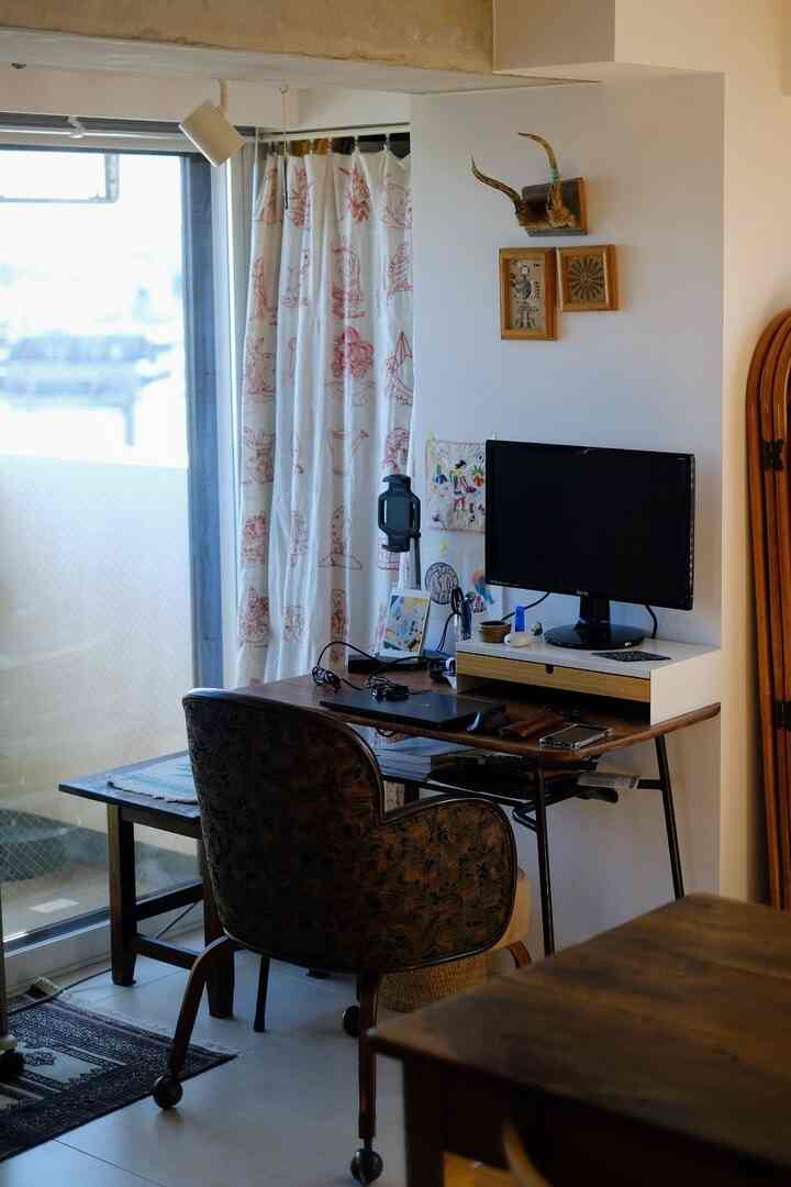 White-walled home office space for remote work featuring a brown desk, comfortable office chair, and patterned curtains creating a cozy atmosphere