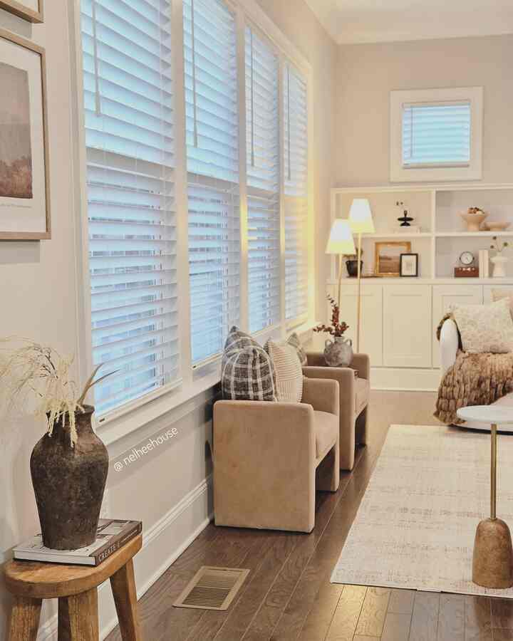 Beige and white toned living room featuring beige armchairs, area rug, and floor lamps with a natural mid-century modern style ambiance