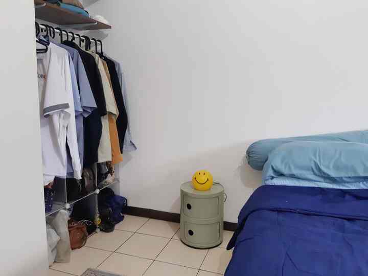 Single household bedroom with white walls and navy bedding, featuring a nightstand topped with a yellow smiley lamp