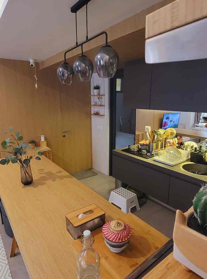 Wood tone and white balanced long kitchen and dining area featuring pendant lights and well-organized countertops with a clean cozy atmosphere
