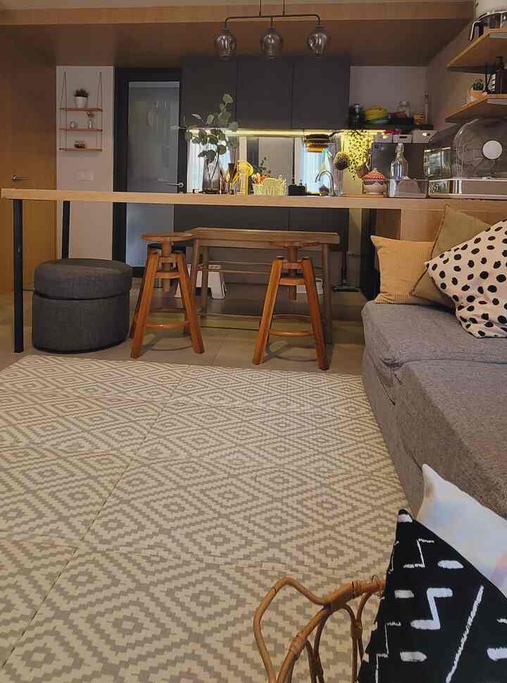 Natural-toned living and dining area featuring wooden stools and a gray sofa creating a cozy interior