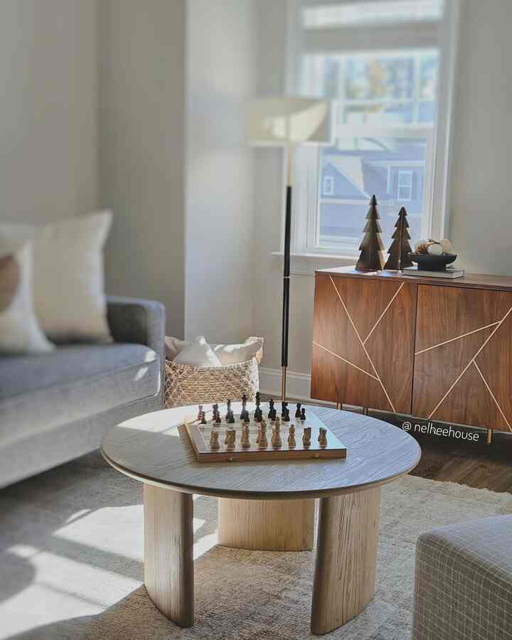 Natural toned living room featuring a round wooden coffee table, wooden cabinet, and gray sofa in a clean minimal design