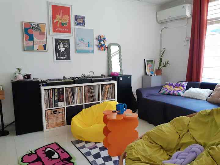 Brightly colored single household living room featuring bean bags, sofa, and posters for a cozy vibe