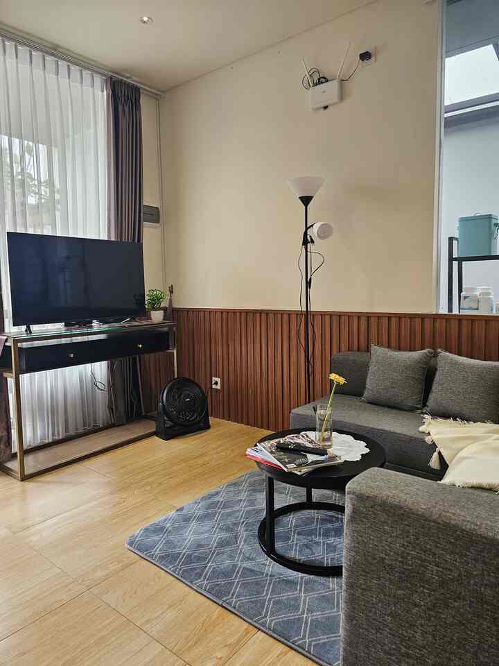 Simple modern small living room with white walls and wood paneling, featuring a gray sofa and black coffee table