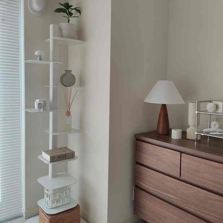 ベージュの壁と木製のチェスト、白い棚が配置されたナチュラルな一人暮らしの小さな部屋のインテリア