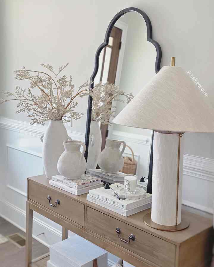 Beige and natural tone entrance space featuring wood console table with unique arched mirror in a simple modern design