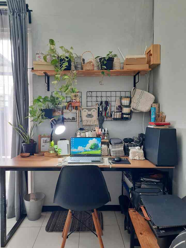 Natural wood tone home office space featuring a black office chair and various plants in a cozy workspace