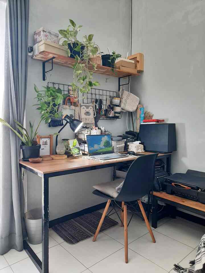 Gray-walled small home office featuring wood-toned desk, shelf with plants, and organized workspace creating a cozy atmosphere