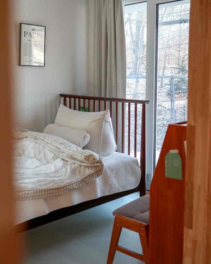 白と木目調の寝室、大きな窓とカーテンが配置された、落ち着いた明るい雰囲気のインテリア