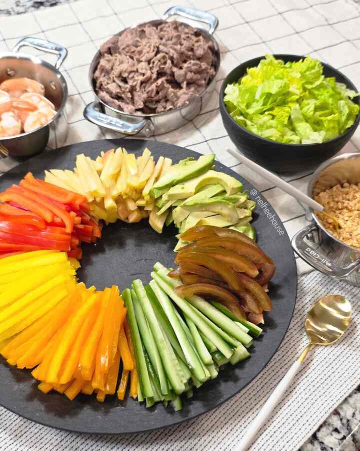 Natural-toned kitchen dining setting featuring fresh vegetables, sliced meats, and neat serving bowls arranged on a dark plate