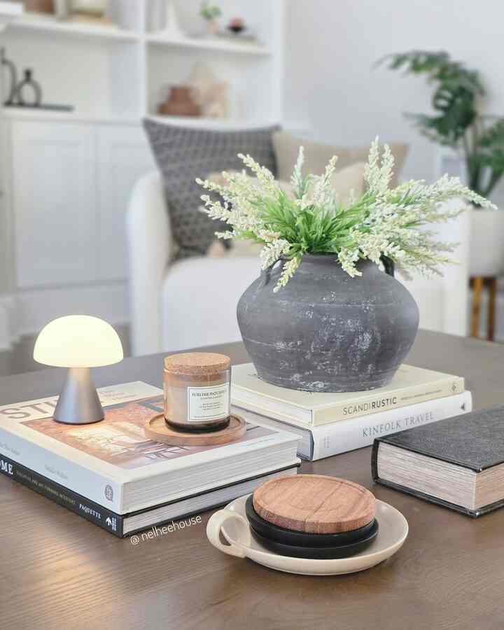 Minimal living room with white walls and chairs, featuring a natural wood coffee table styled with a vase, candle, and mini lamp