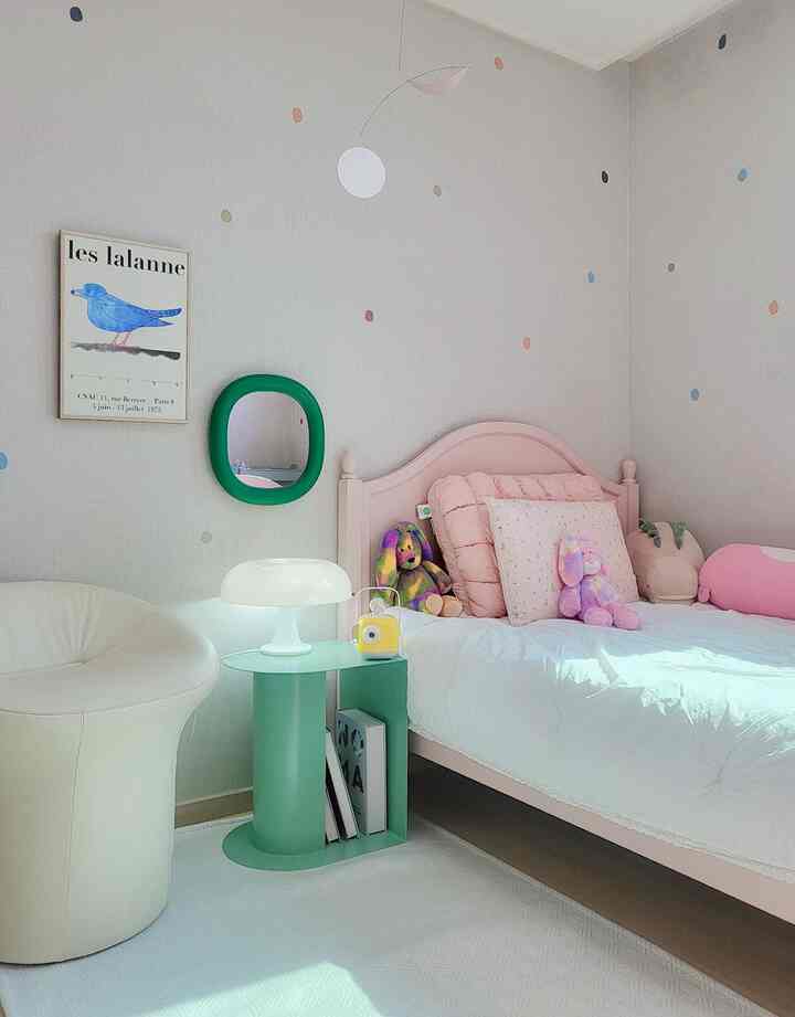 Pastel pink and white kids' room featuring a pink bed and mint side table with a cozy atmosphere