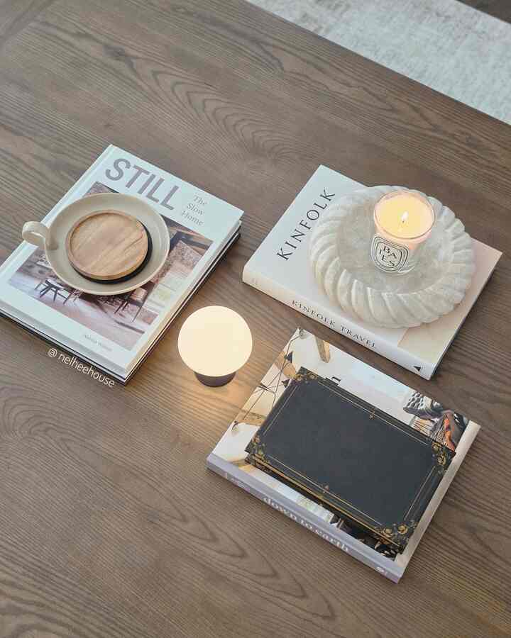 Natural brown wood tone coffee table styled with minimal books, candle, and tray creating a cozy living room atmosphere