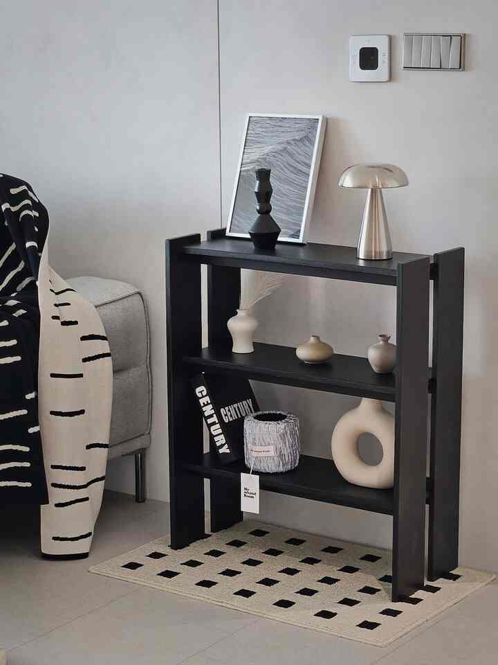 Neutral-toned living room corner featuring a black Onheuk shelf decorated with a silver table lamp and stylish decor, creating a modern atmosphere