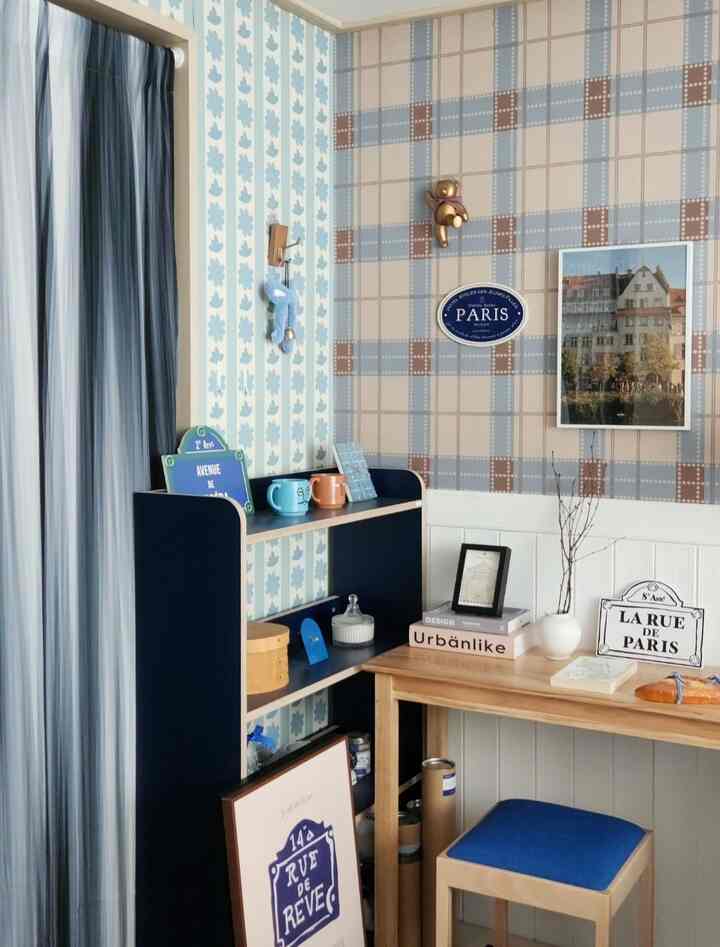 Pastel-toned wallpaper with natural wooden console table and blue curtain in a cozy cafe-style small room interior