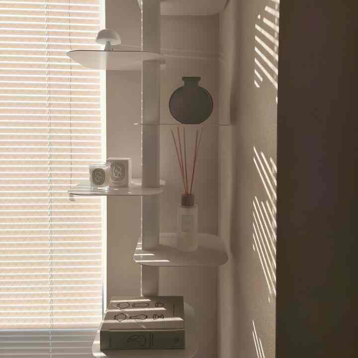 White and beige toned Korean interior living space featuring blinds and shelves with interior accessories in a calm atmosphere